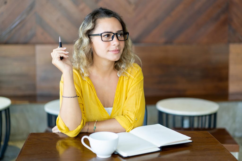 Pretty-curly-young-woman-writing-notes-startup-project